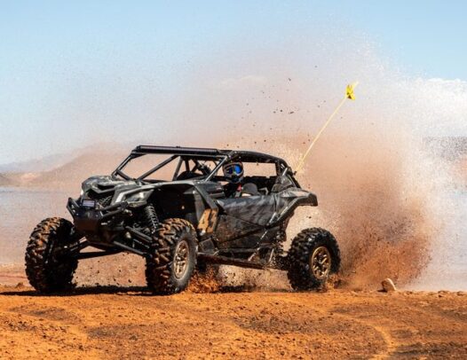 Dune buggy driving through Dubai desert sands under clear blue sky – off-road adventure