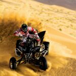 Adventurer riding a quad bike through the Dubai desert with golden dunes in the background