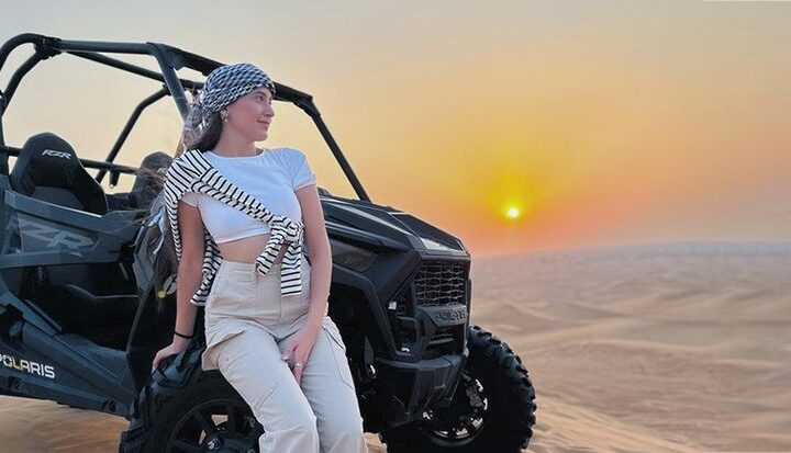 Dune buggy driving through sand dunes in Dubai under clear skies