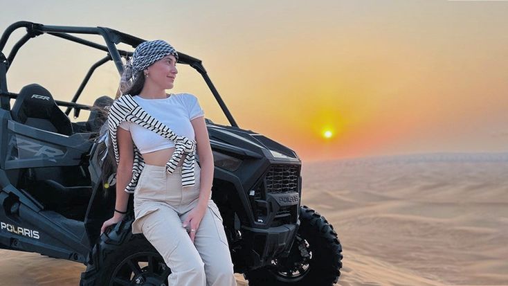 Dune buggy driving through sand dunes in Dubai under clear skies