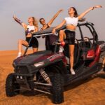 Man driving a dune buggy over golden desert dunes during a Dubai adventure tour
