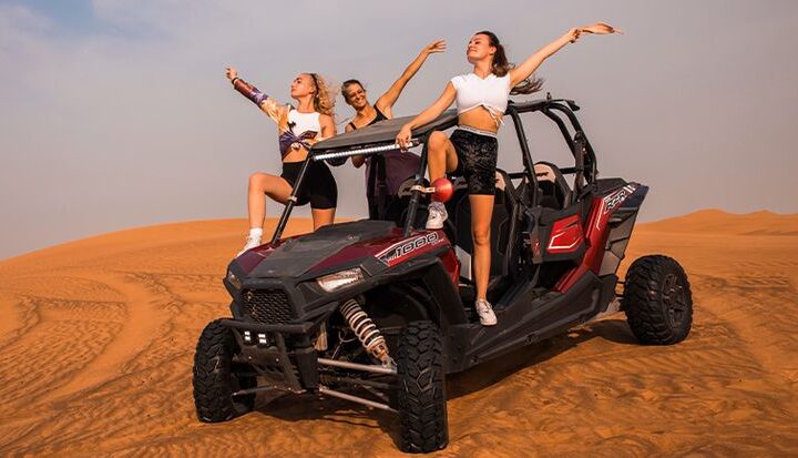 Man driving a dune buggy over golden desert dunes during a Dubai adventure tour