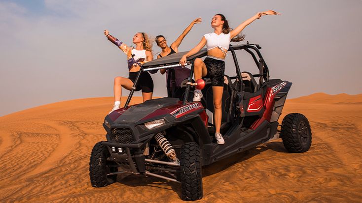 Man driving a dune buggy over golden desert dunes during a Dubai adventure tour