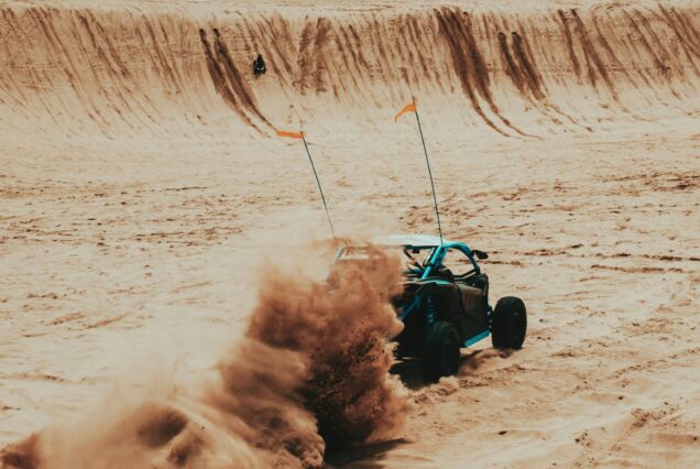 Can-Am buggy driving through Dubai desert dunes during sunset