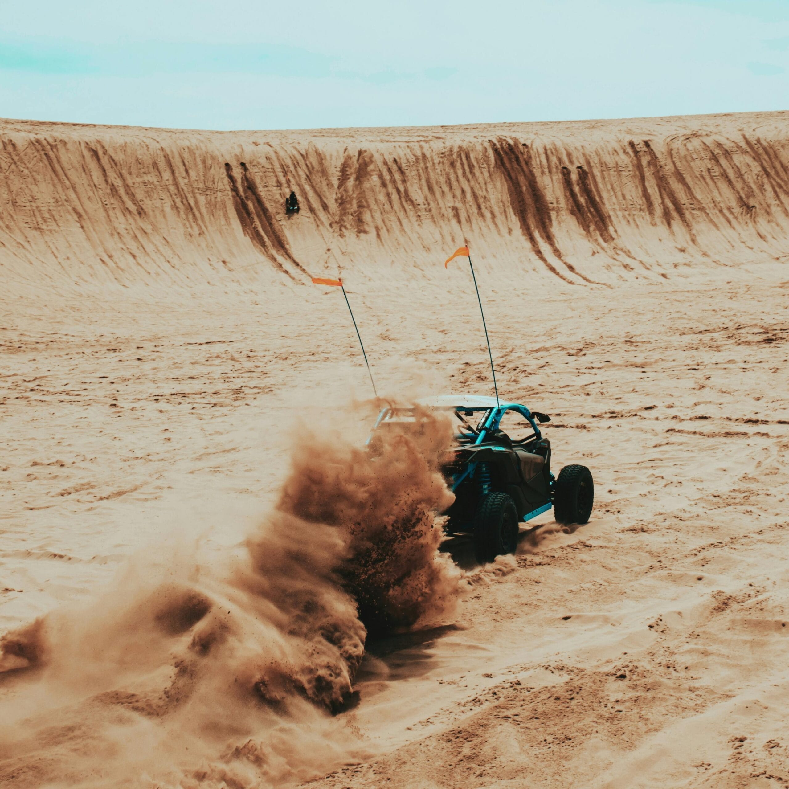 Can-Am buggy driving through Dubai desert dunes during sunset