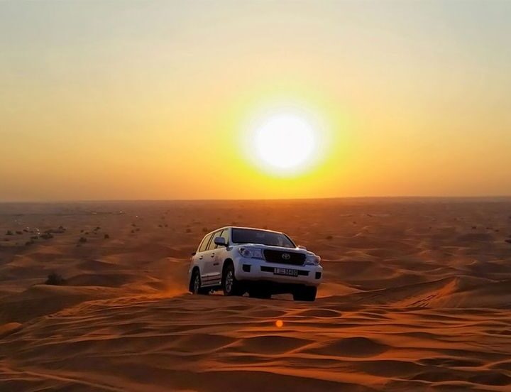 Midday desert safari in Dubai with 4x4 vehicle and golden sand dunes under bright sunlight